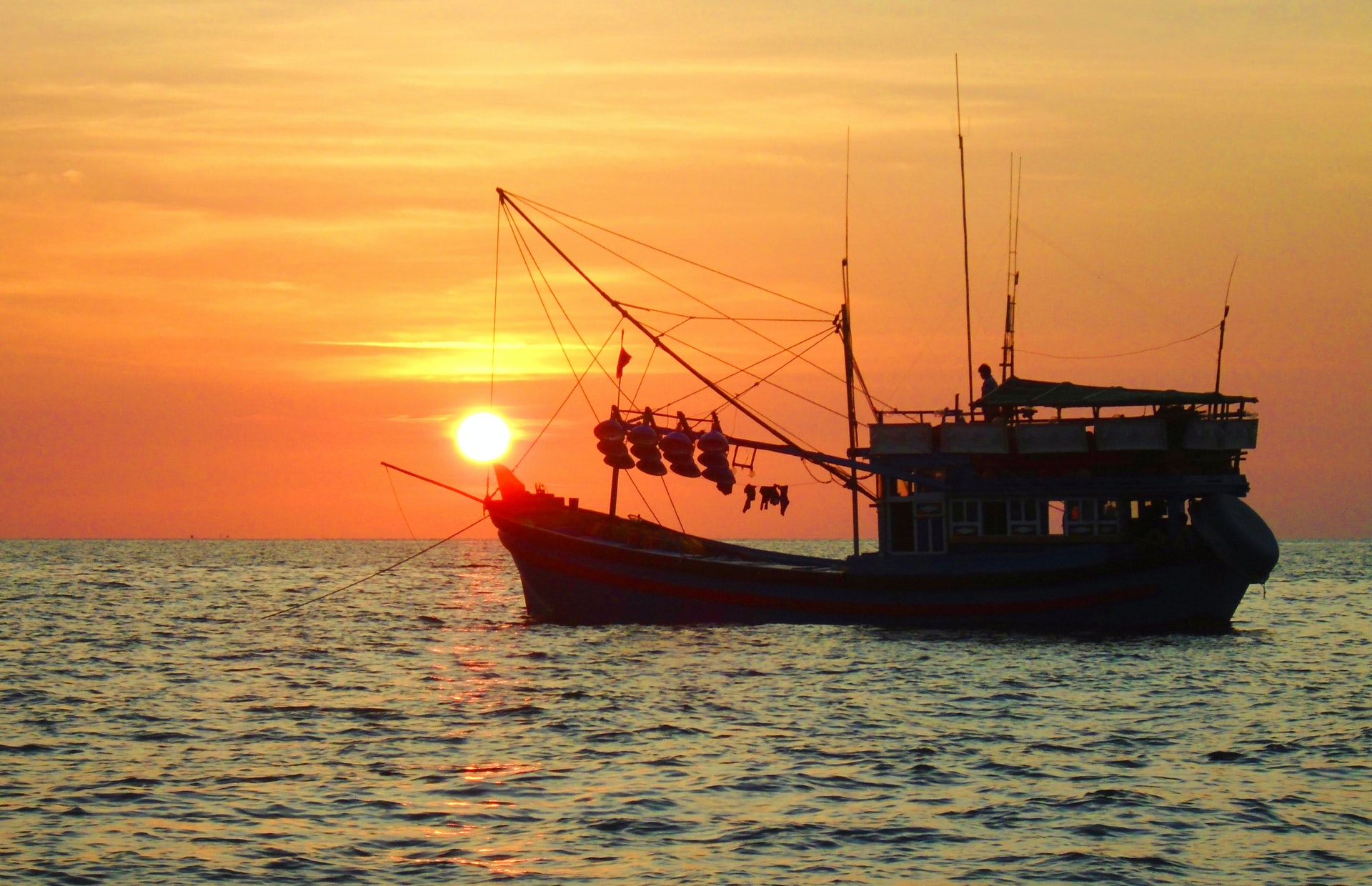Tàu đánh cá trên mặt biển dưới ánh hoàng hôn